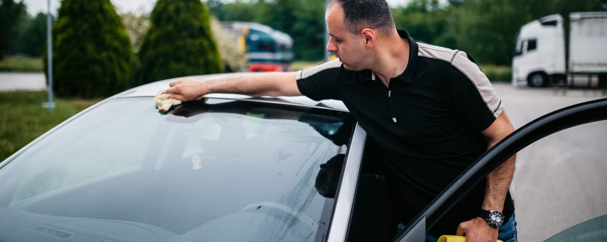 Man cleaning the windshield of a car using microfiber cloth